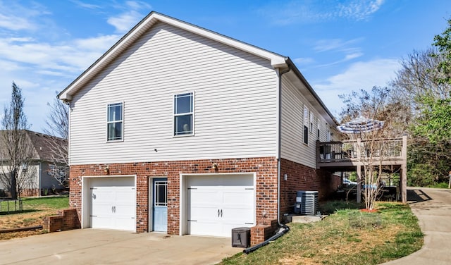 view of side of property featuring brick siding, central air condition unit, driveway, and an attached garage