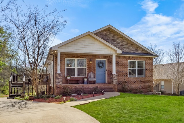 view of front of property featuring a front yard, brick siding, and covered porch
