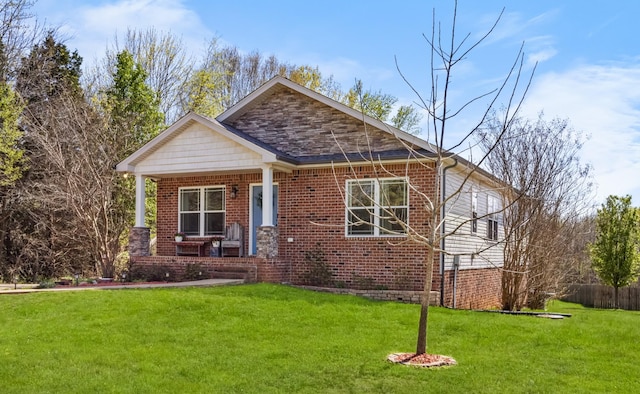 view of front of home with a porch, a front yard, and brick siding
