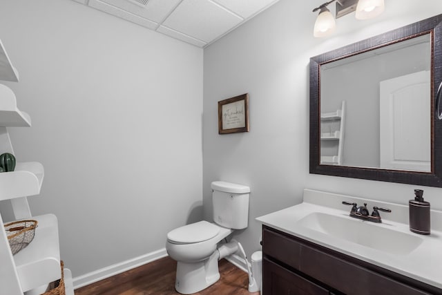 bathroom featuring toilet, vanity, wood finished floors, and baseboards