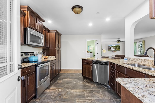 kitchen featuring a sink, light stone countertops, arched walkways, and stainless steel appliances