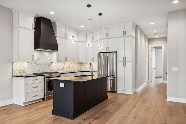 kitchen featuring light wood-style flooring, appliances with stainless steel finishes, a sink, dark countertops, and custom range hood