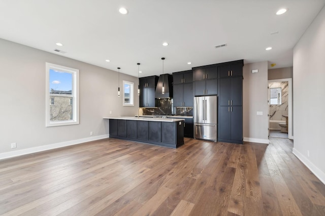 3207A Long Blvd, Nashville, TN 37203 - kitchen featuring a peninsula, wall chimney range hood, high end refrigerator, light countertops, and hardwood / wood-style flooring