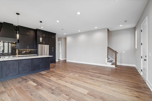 3207A Long Blvd, Nashville, TN 37203 - kitchen featuring wall chimney range hood, light countertops, appliances with stainless steel finishes, open floor plan, and light wood-style flooring