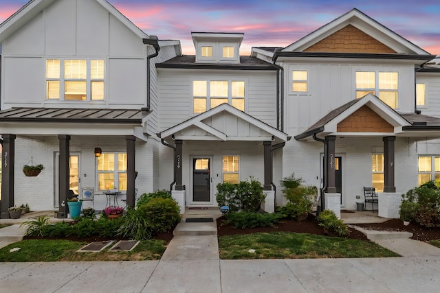 townhome / multi-family property featuring a standing seam roof, covered porch, and brick siding