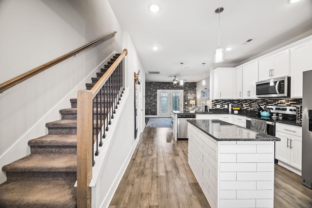 kitchen with a peninsula, white cabinetry, appliances with stainless steel finishes, and wood finished floors