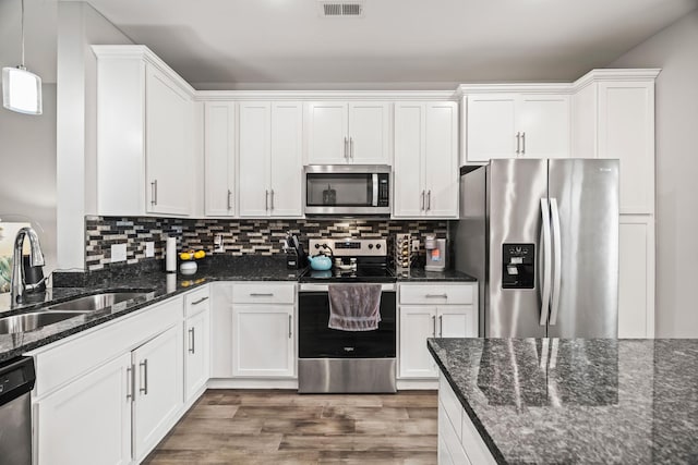 kitchen with visible vents, appliances with stainless steel finishes, wood finished floors, a sink, and white cabinetry