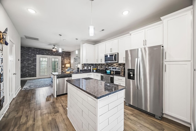 kitchen featuring a kitchen island, appliances with stainless steel finishes, dark wood finished floors, white cabinets, and a peninsula