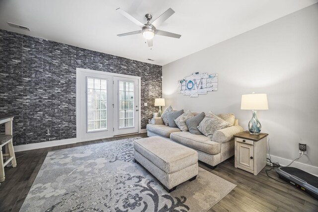 living room with a ceiling fan, baseboards, visible vents, and dark wood-type flooring