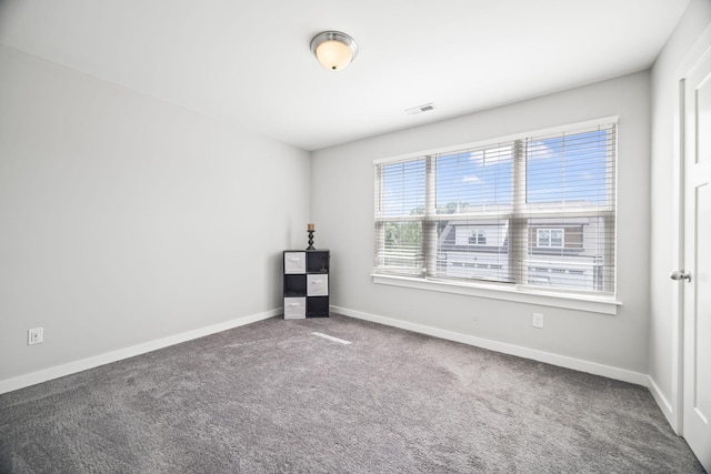 carpeted empty room featuring baseboards and visible vents