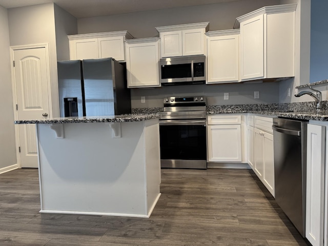 kitchen featuring dark stone counters, dark wood-type flooring, appliances with stainless steel finishes, and white cabinetry