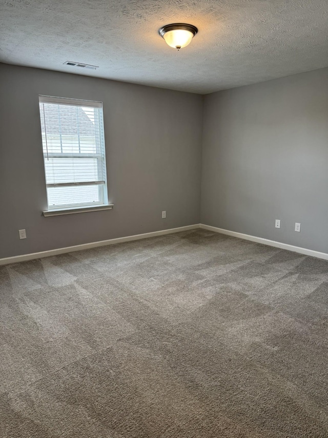 carpeted empty room with visible vents, a textured ceiling, and baseboards