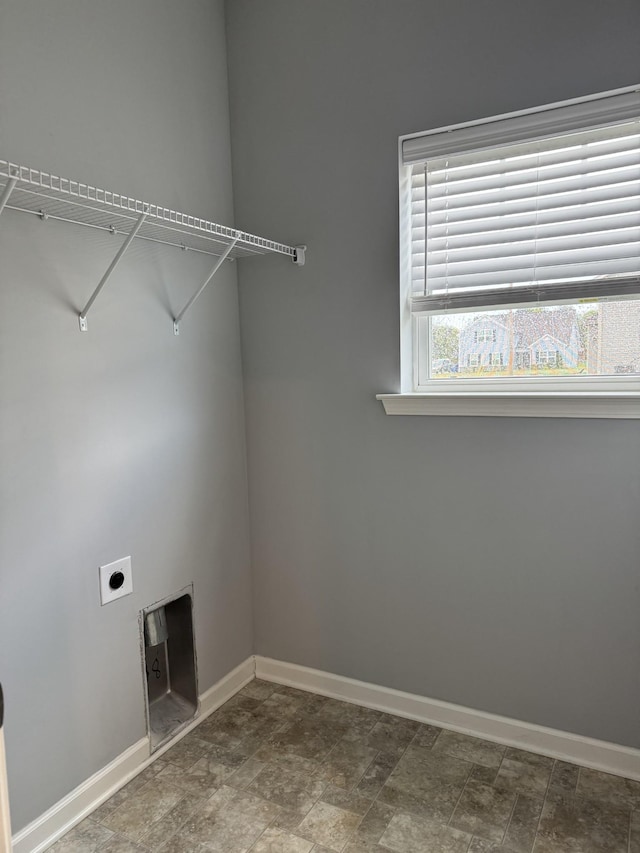 washroom with baseboards, electric dryer hookup, stone finish floor, and laundry area