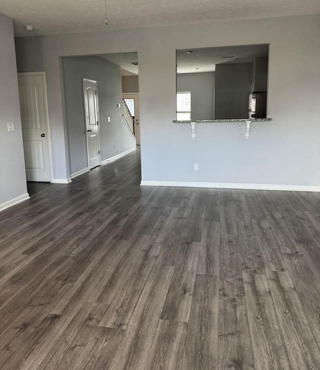 spare room featuring dark wood-style flooring and baseboards