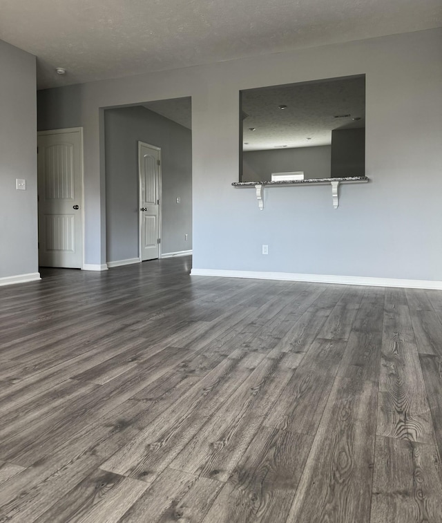 unfurnished living room with dark wood-type flooring and baseboards