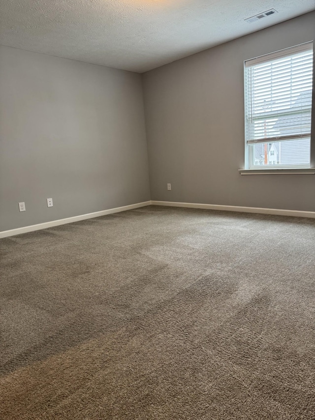 empty room featuring visible vents, carpet flooring, and a textured ceiling