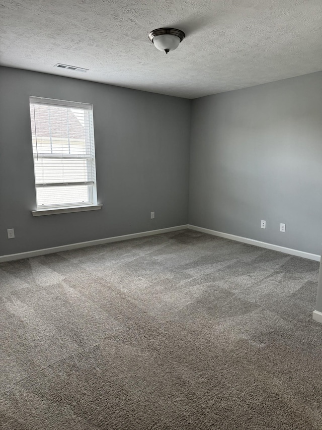 empty room featuring carpet flooring, baseboards, and a textured ceiling