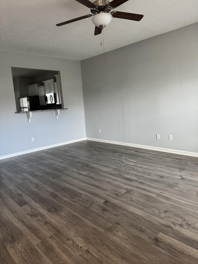 unfurnished living room featuring a textured ceiling, ceiling fan, baseboards, and dark wood-style flooring