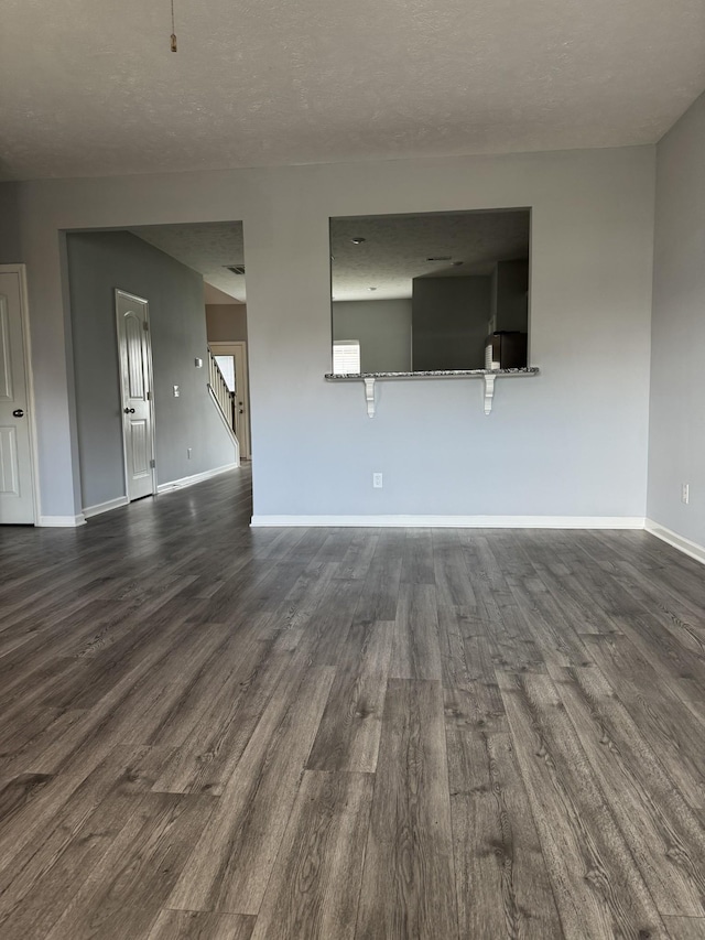interior space featuring a textured ceiling, baseboards, and dark wood finished floors