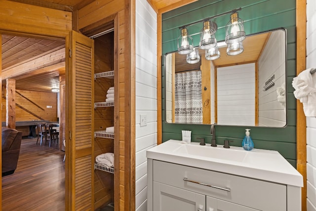bathroom featuring wooden walls, vanity, and wood finished floors