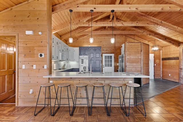 kitchen with wooden walls, stainless steel refrigerator, wooden ceiling, and white double oven