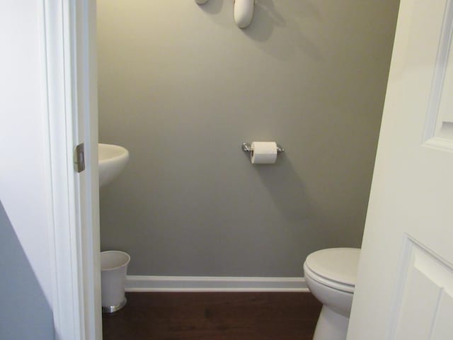 bathroom with toilet, wood finished floors, ceiling fan, and baseboards