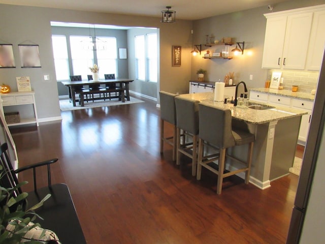 kitchen with a sink, tasteful backsplash, white cabinetry, and dark wood-type flooring