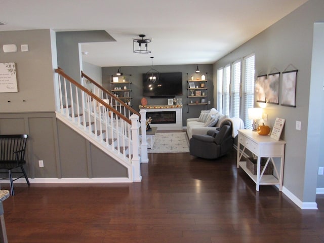 living room with visible vents, stairway, wood finished floors, and a glass covered fireplace