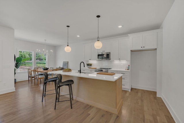 kitchen featuring tasteful backsplash, a sink, light countertops, appliances with stainless steel finishes, and light wood finished floors