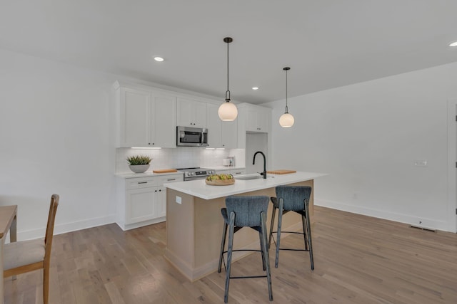 kitchen featuring a sink, white cabinets, light wood finished floors, and stainless steel appliances