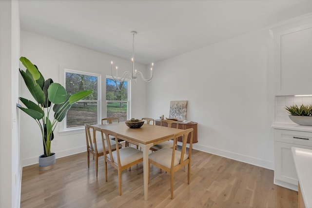 dining room with light wood-style flooring, baseboards, and an inviting chandelier