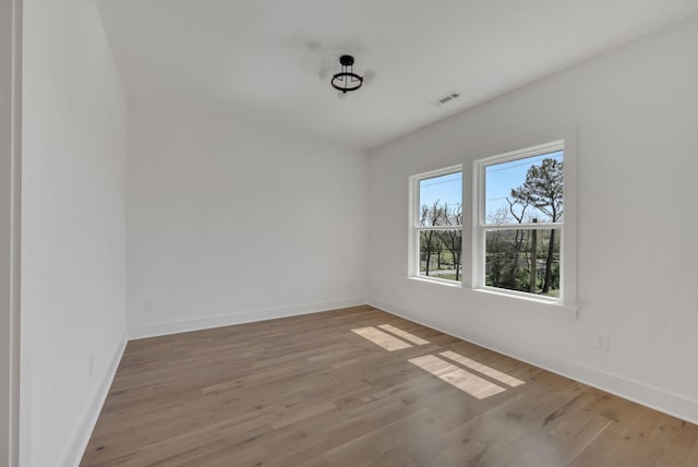 unfurnished room featuring wood finished floors, baseboards, and visible vents