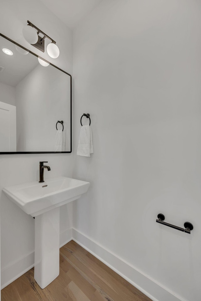 bathroom with wood finished floors, a sink, baseboards, and visible vents