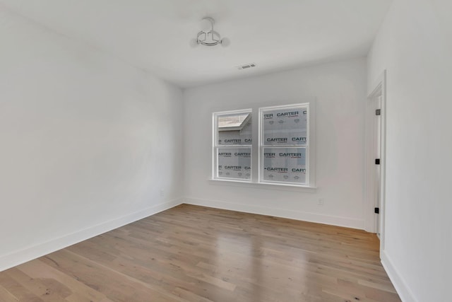 spare room with wood finished floors, baseboards, and visible vents