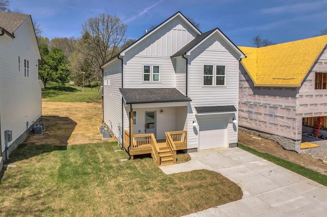 rear view of house featuring board and batten siding, cooling unit, an attached garage, a shingled roof, and driveway