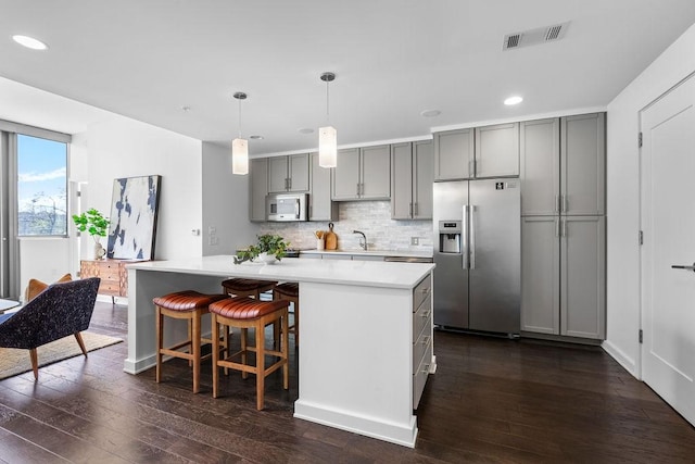 kitchen featuring stainless steel fridge with ice dispenser, gray cabinetry, white microwave, and visible vents