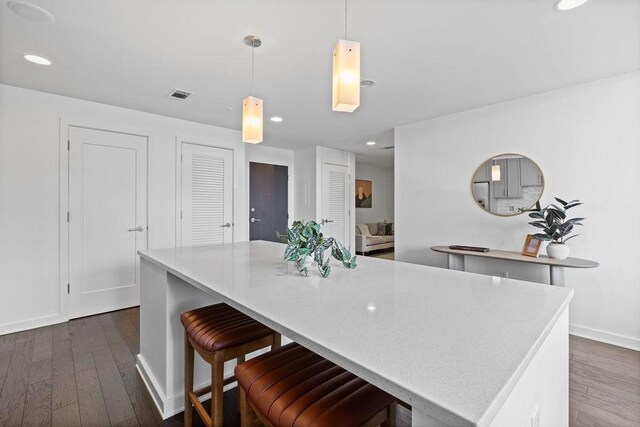 kitchen with dark wood-style flooring, visible vents, light countertops, and hanging light fixtures