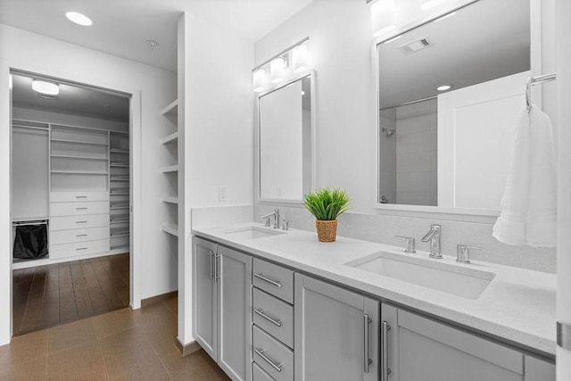 full bath featuring double vanity, a sink, a spacious closet, and visible vents