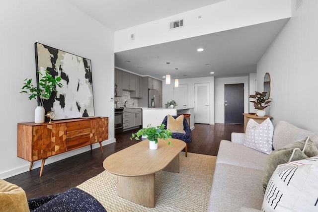 living area with dark wood-style flooring, baseboards, visible vents, and recessed lighting