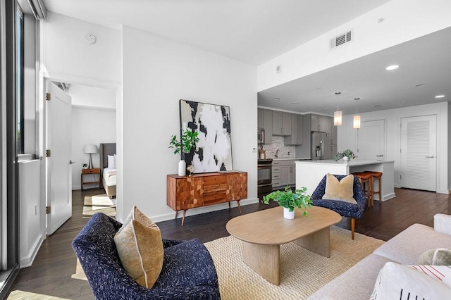 living room featuring visible vents, baseboards, recessed lighting, and wood finished floors