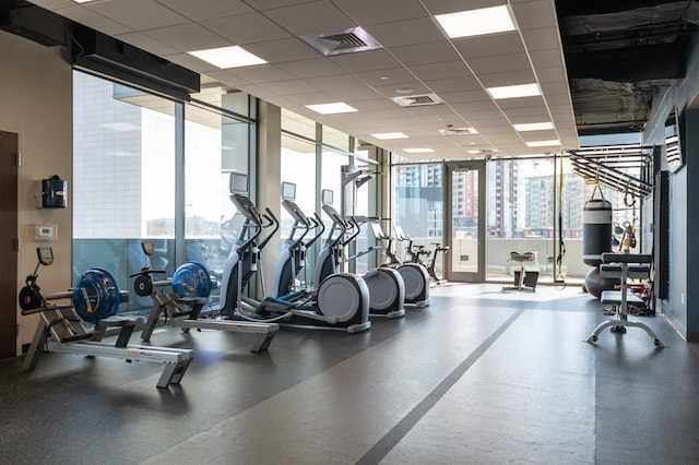 exercise room with visible vents, a paneled ceiling, and a wall of windows