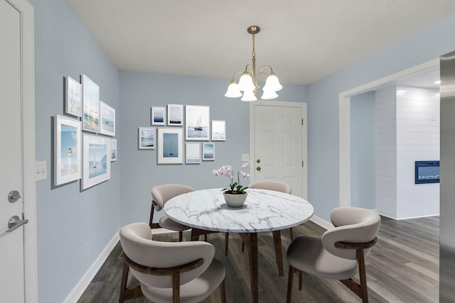 314 Shadowbrook Dr, Smyrna, TN 37167 - dining area featuring a textured ceiling, baseboards, dark wood-style flooring, a notable chandelier, and a glass covered fireplace