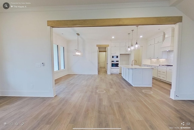 kitchen featuring oven, premium range hood, light wood-type flooring, light countertops, and white cabinetry