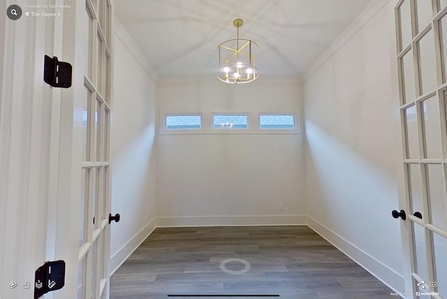 unfurnished dining area featuring french doors, crown molding, baseboards, an inviting chandelier, and dark wood-type flooring
