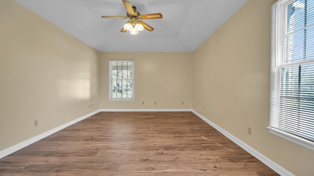 empty room with baseboards, a ceiling fan, and dark wood finished floors