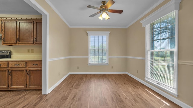 unfurnished dining area featuring light wood-style floors, baseboards, ornamental molding, and ceiling fan