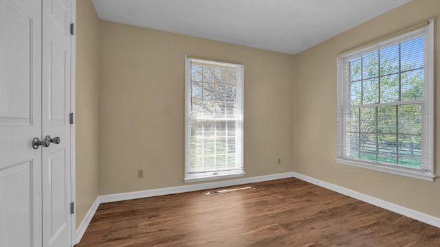 empty room featuring dark wood-style flooring and baseboards