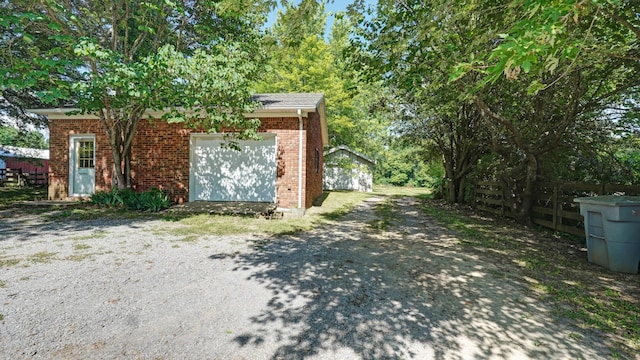 view of side of property with brick siding, driveway, fence, and an attached garage