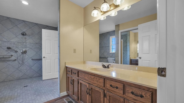 full bathroom with a tile shower, vanity, visible vents, and toilet