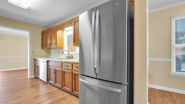 kitchen featuring light wood-style flooring, light countertops, freestanding refrigerator, dishwashing machine, and a sink